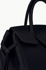 Maude carryall bag close-up in black with textured finish and front flap detail.