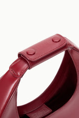 Maroon mini moon bag strap detail with snap button and stitched handle