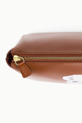 Tan zipper pouch close-up with gold zipper and leather-look strap pull.