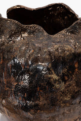 Textured ceramic vase close-up, dark speckled glaze with glossy highlights and open rim