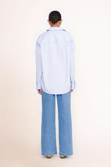Light blue oversized button-up shirt from back view with yoke seam and full length sleeves