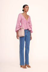 Blush leather mini tote bag held by model by the top handle