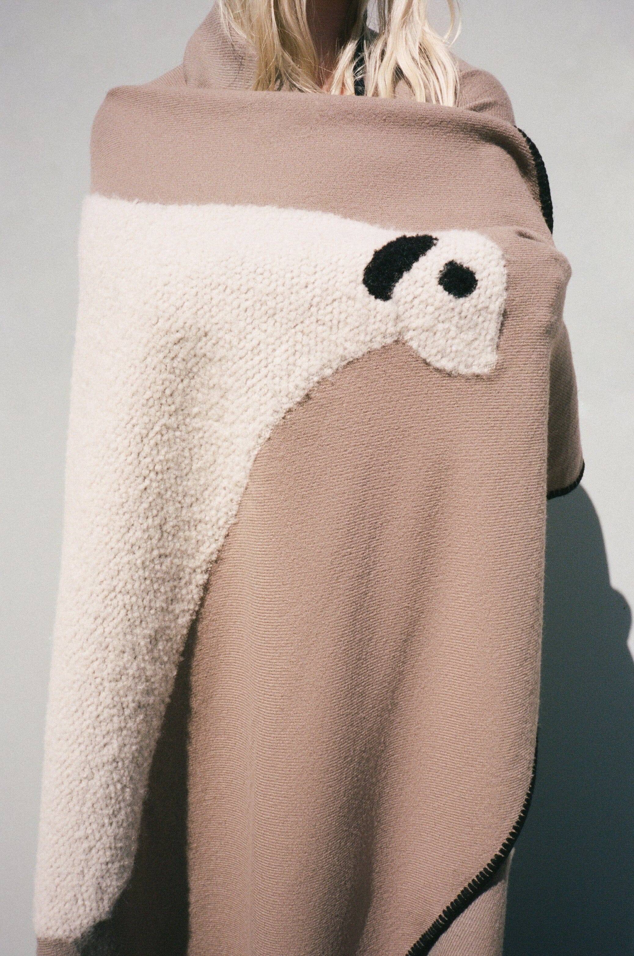 Back view of sheep throw blanket draped in truffle taupe with cream sheep motif