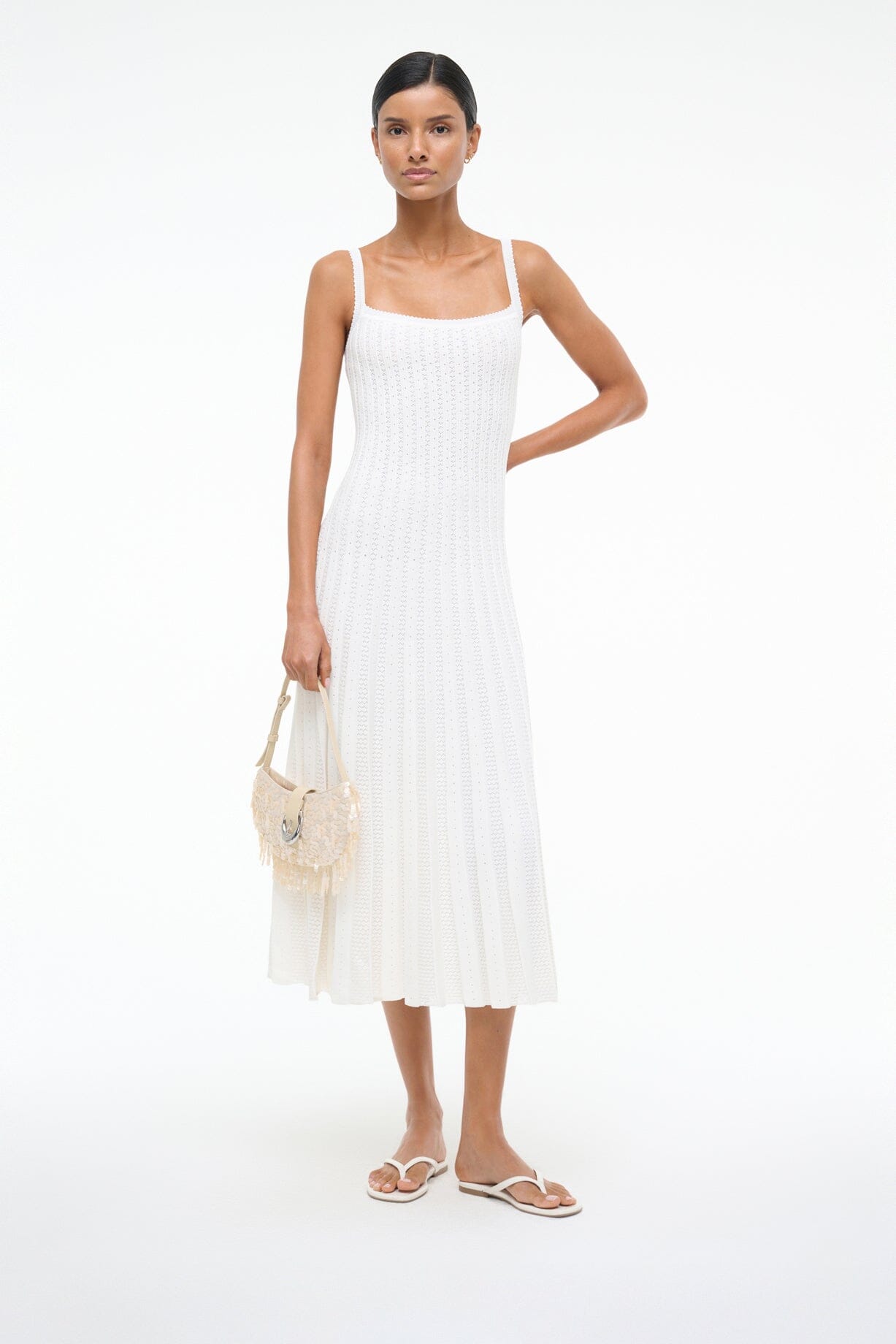White thong sandals with thin toe strap and flat sole, worn with a white dress