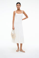 White thong sandals with thin toe strap and flat sole, worn with a white dress