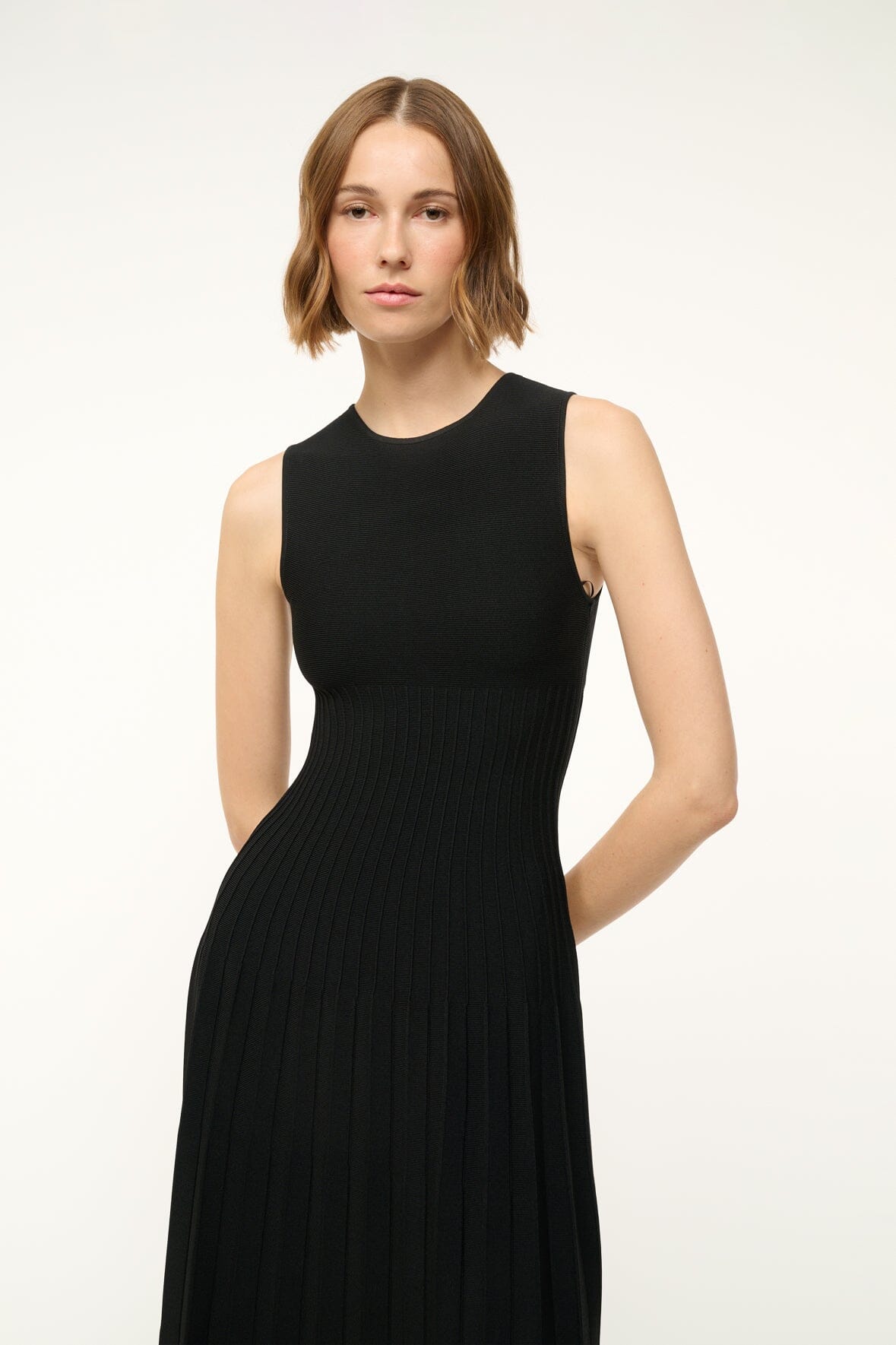 Black sleeveless midi knit dress, crew neck, fitted waist, pleated skirt folds