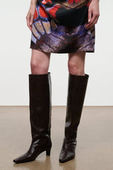 Knee-high heeled boot in dark espresso brown snake-embossed leather, sleek silhouette.
