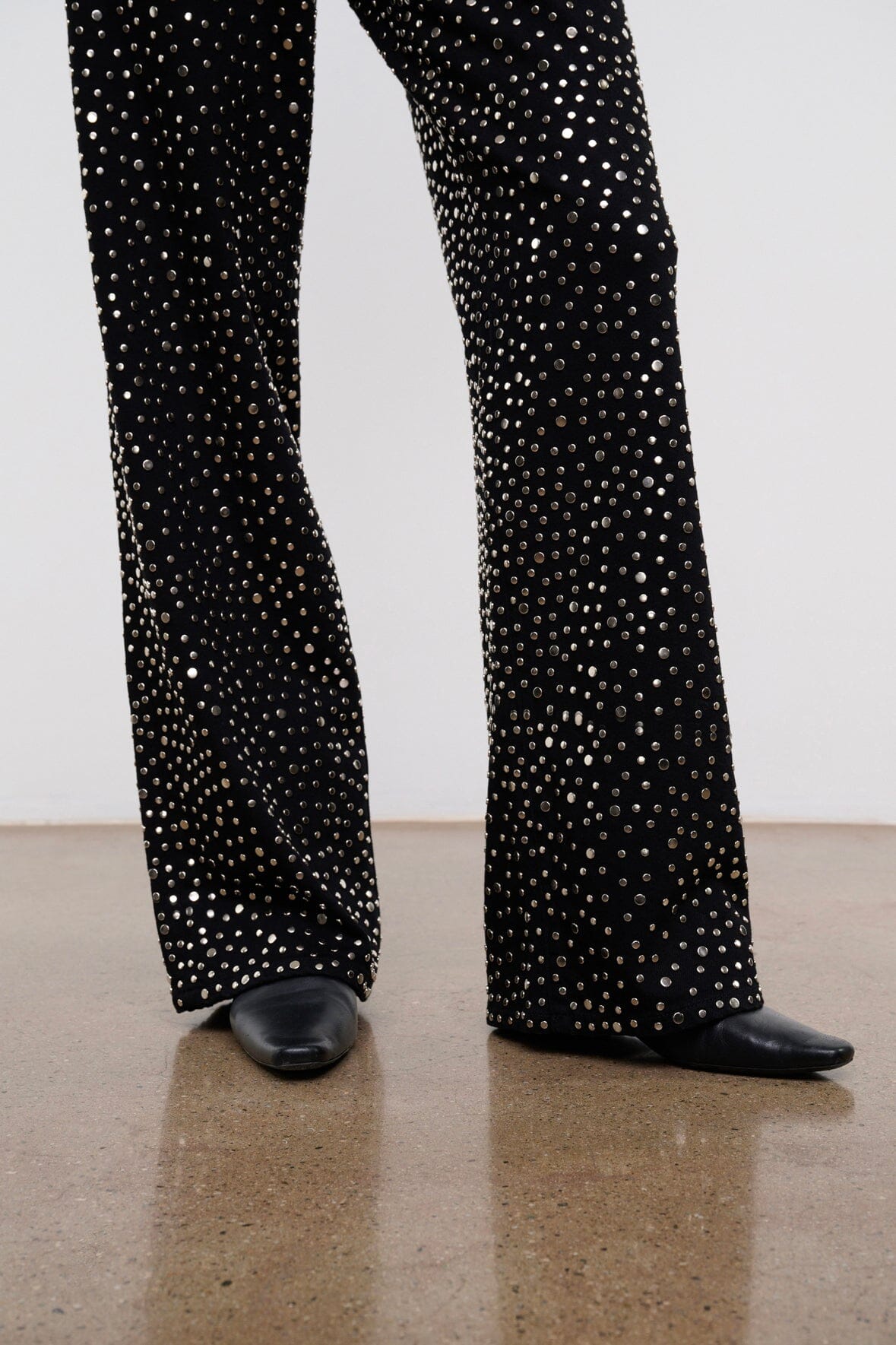 Black studded wide-leg jeans showing full leg coverage from hem to cuff.