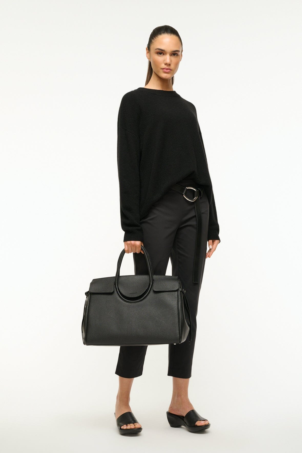 Maude carryall bag in black worn over shoulder with silver ring hardware.