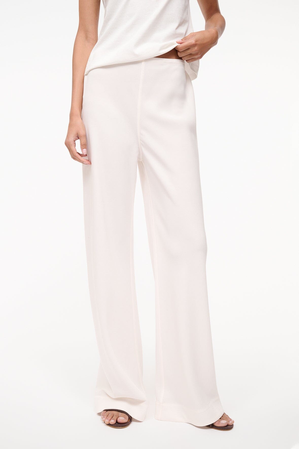 Ivory wide-leg trousers worn straight down the leg for a relaxed fit.