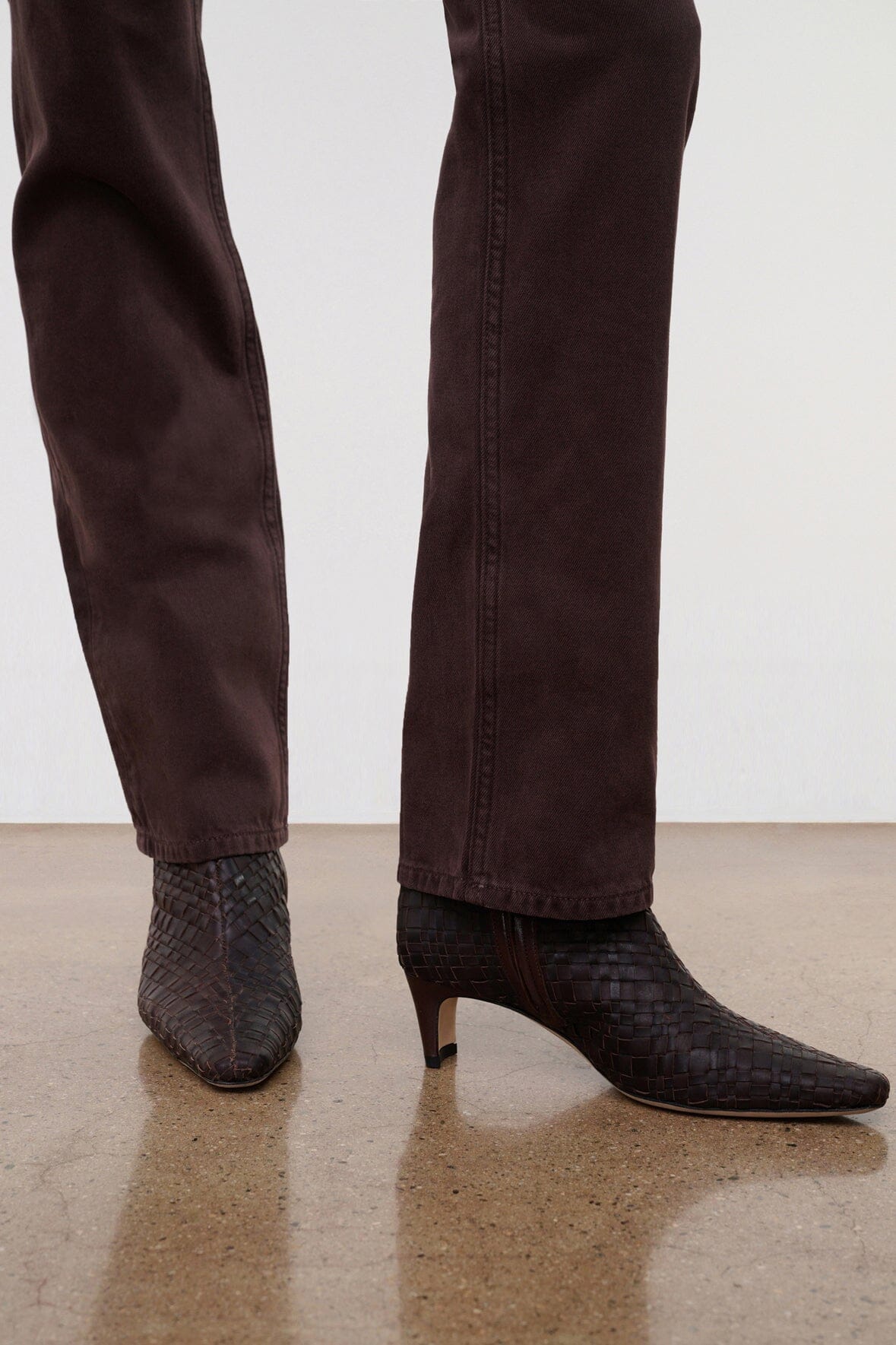 Dark brown straight jeans on model, full leg with stitched hem