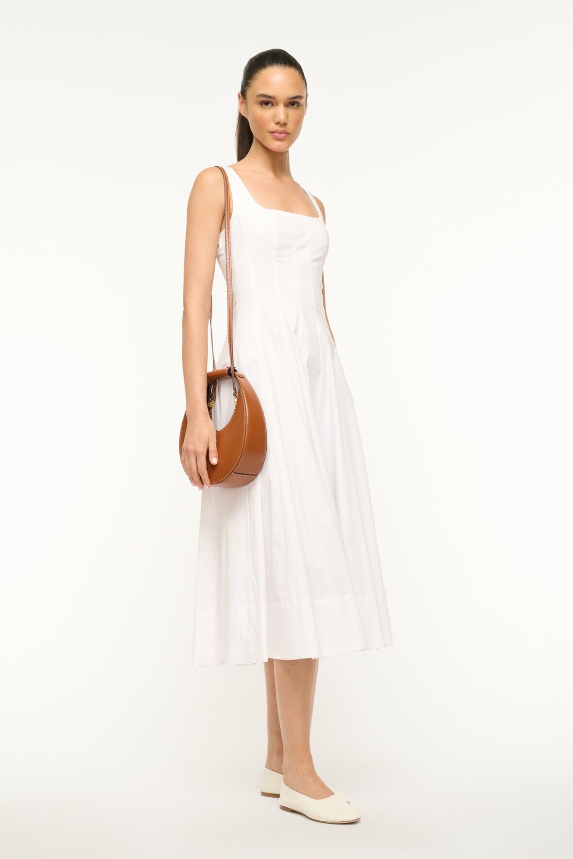 Mini moon bag tan leather carried at side with round top handle.
