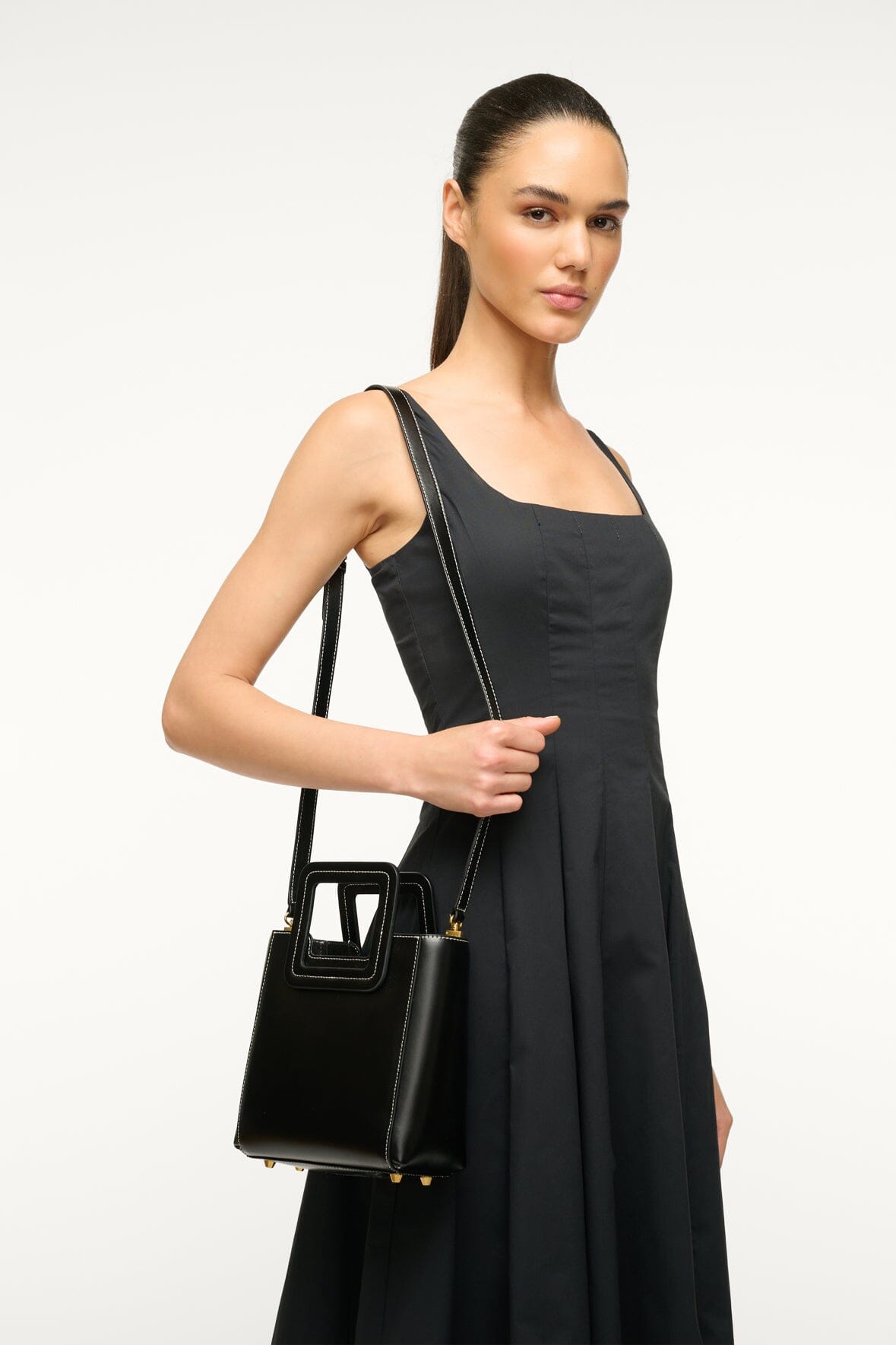 Black leather mini bag with crossbody strap, top handle, and gold-tone hardware