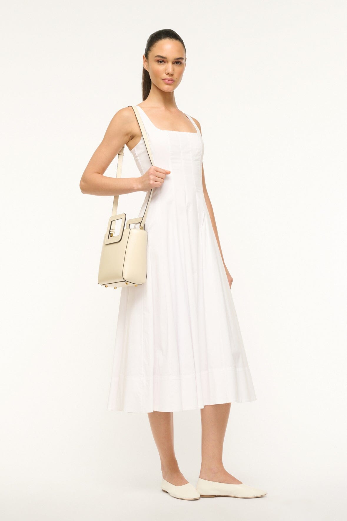 Model wearing mini cream leather bag with top handle and crossbody style pouch