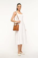 Saddle brown mini leather top-handle bag worn across the body with front clasp
