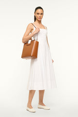 Tan leather bag carried at side with top handle