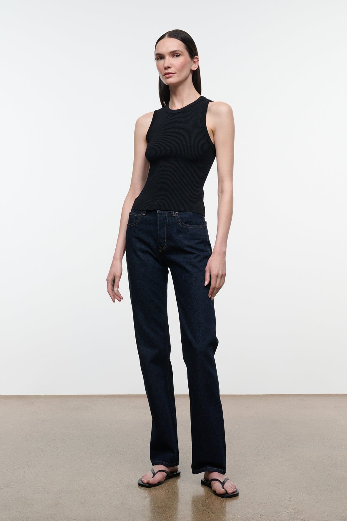 Black ribbed crew-neck tank top worn with dark wide-leg jeans