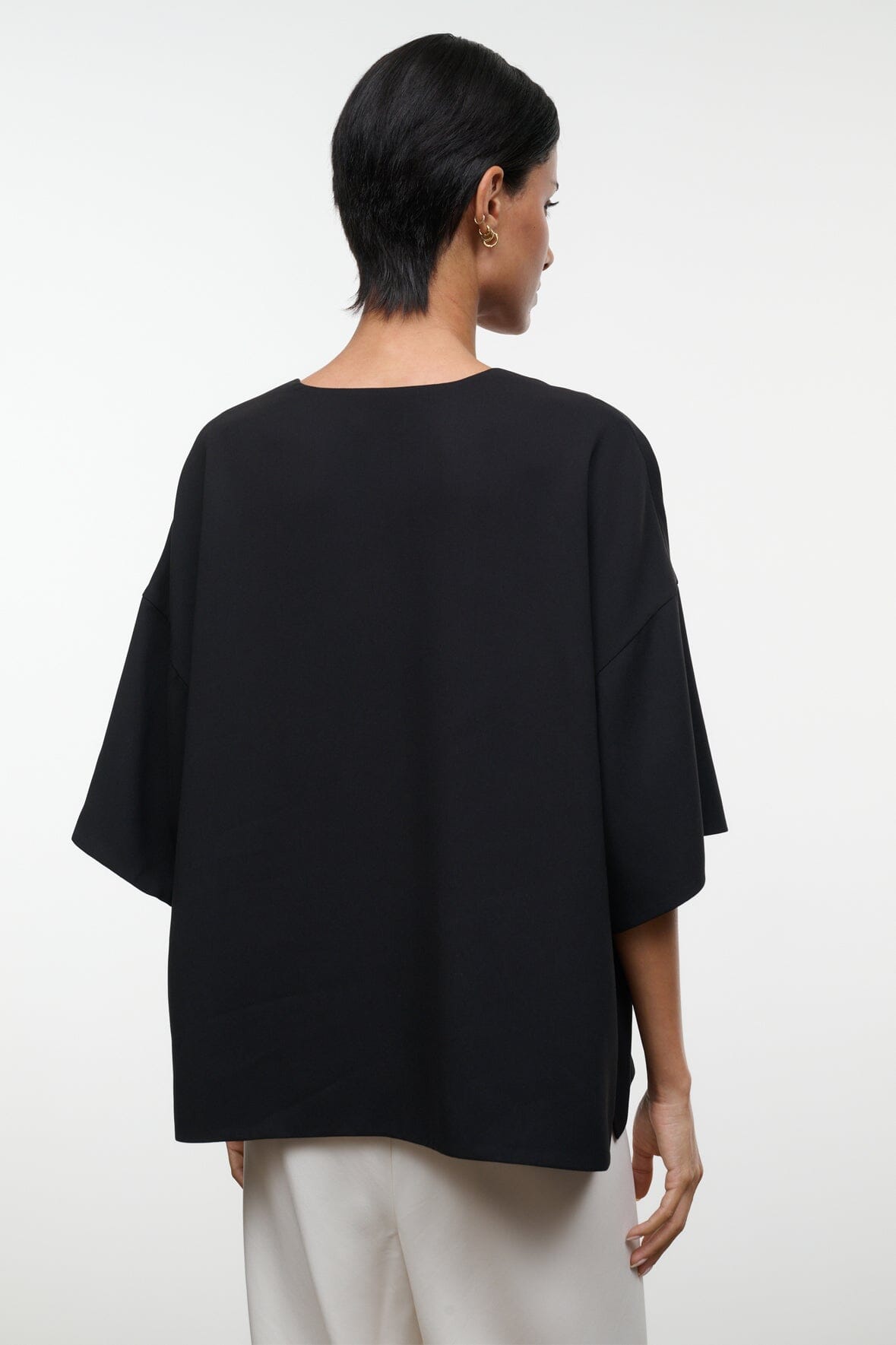 Back view of black studio tee with short sleeves and relaxed, boxy fit