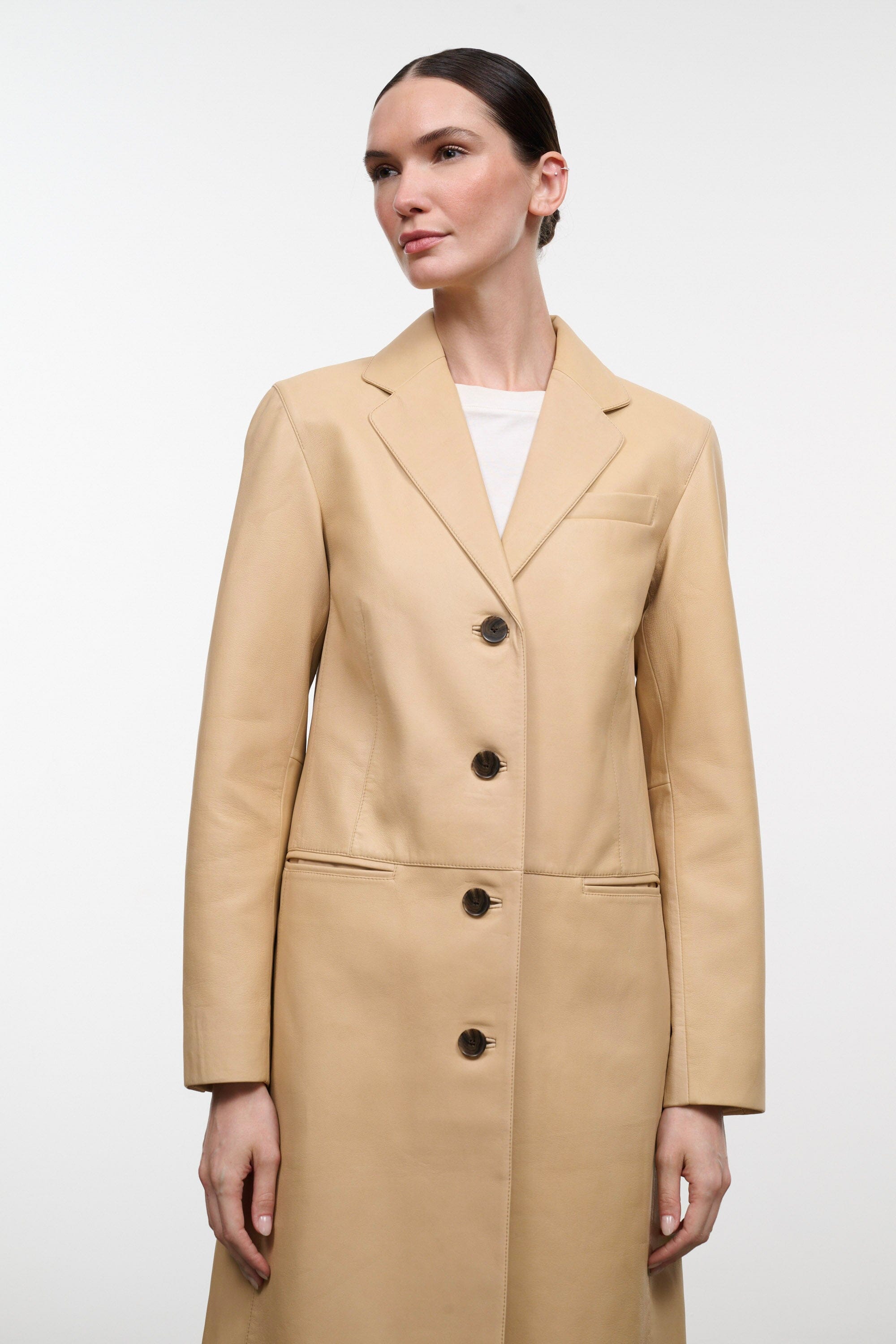 Women's tan leather coat with notch lapel, center buttons, and side pockets