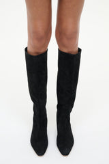 Black suede flat knee boots on legs with pull-on shaft and low heel