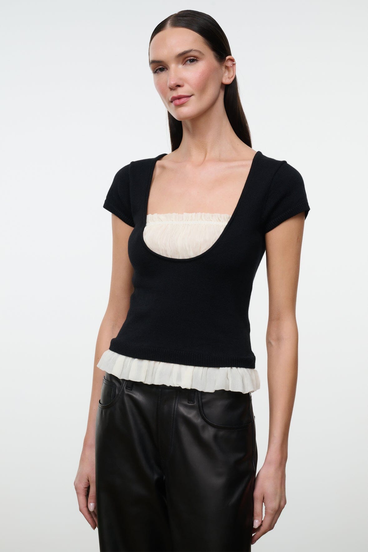 Black scoop-neck knit top with ivory peplum-like ruffle trim
