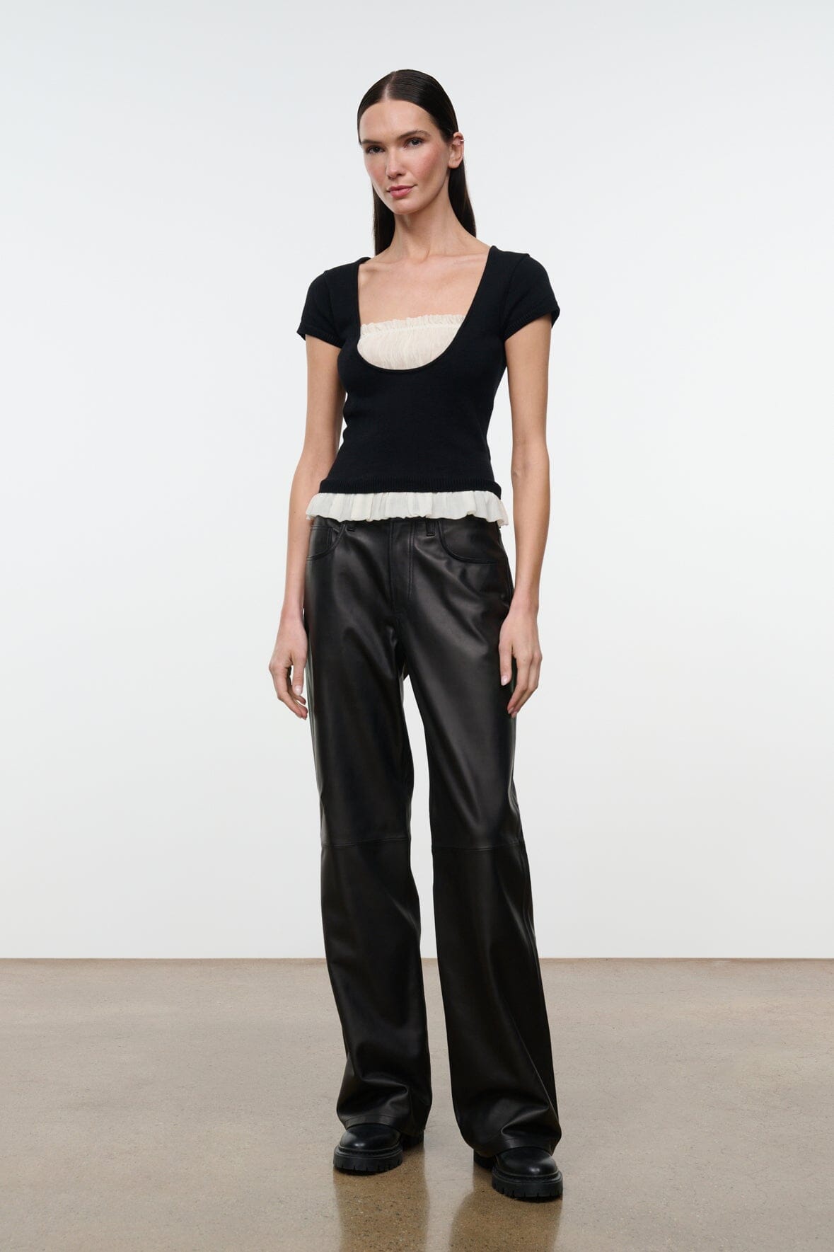 Black knit top with scoop neckline and ivory ruffled hem