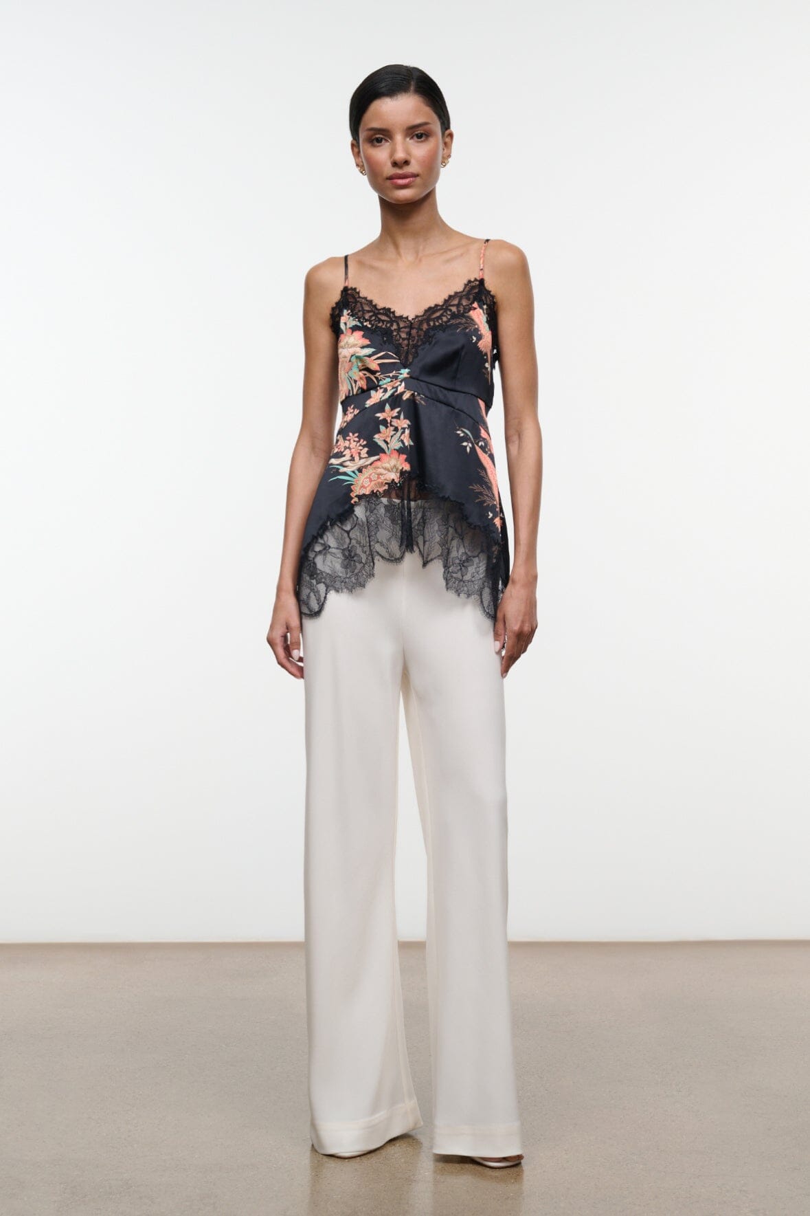 Noir floral silk camisole top with lace hem and adjustable straps, worn with white trousers
