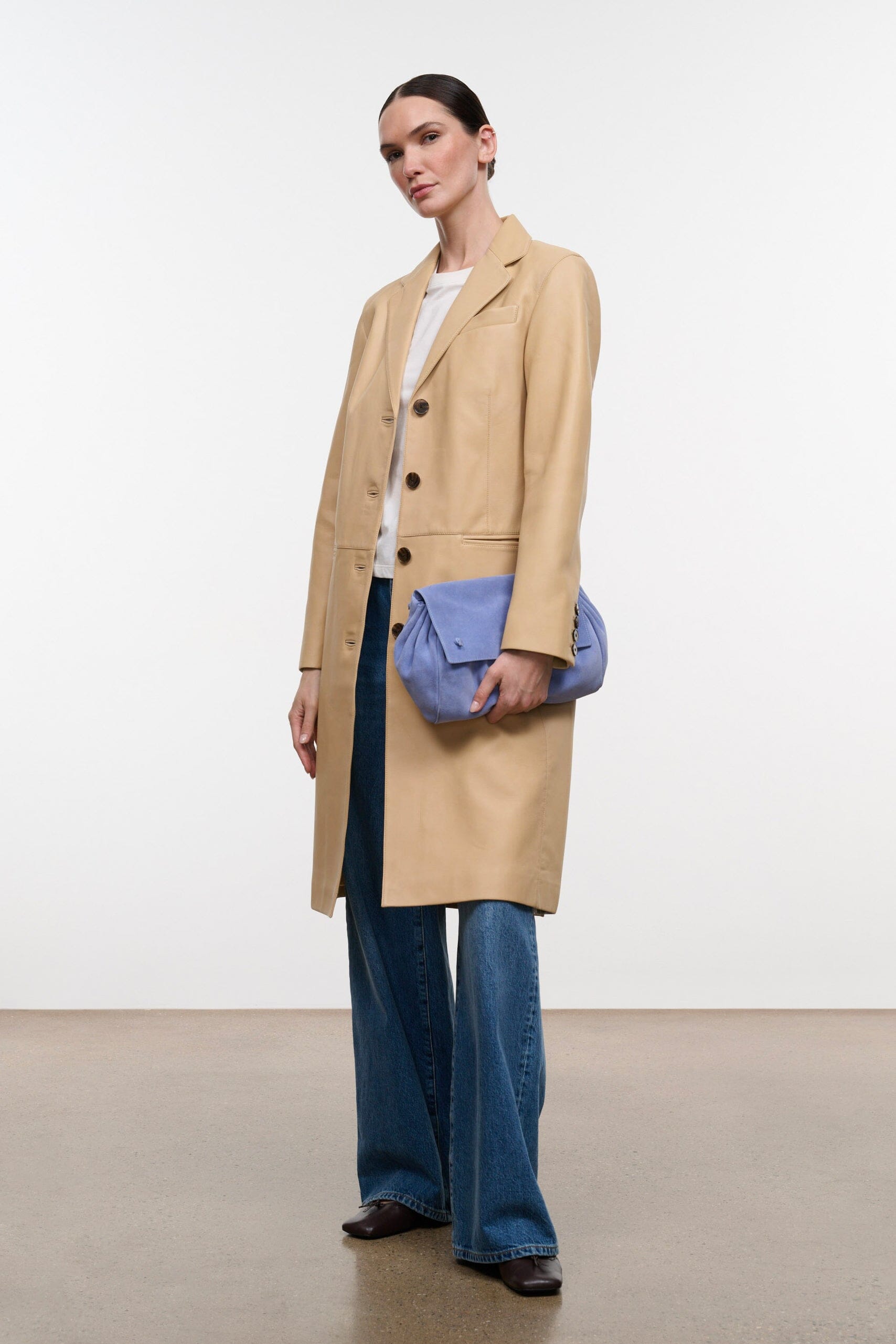 Women's tan leather coat with button front, side seam detail, and long hem