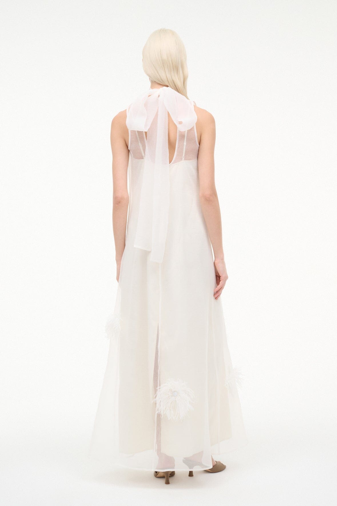 White sleeveless long dress, open back with feather-trim accents along panels