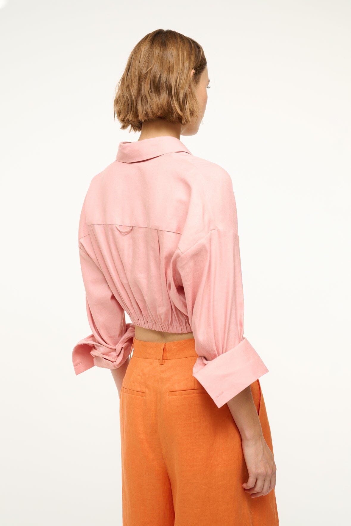 Faded blush linen button-up top, back view, with tie at waist and rolled sleeves