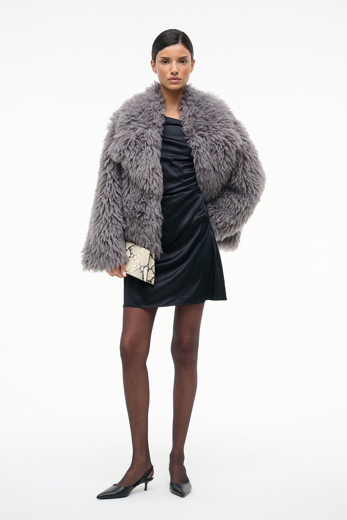 Black one-shoulder mini silk dress with draped bodice, styled with gray faux fur wrap