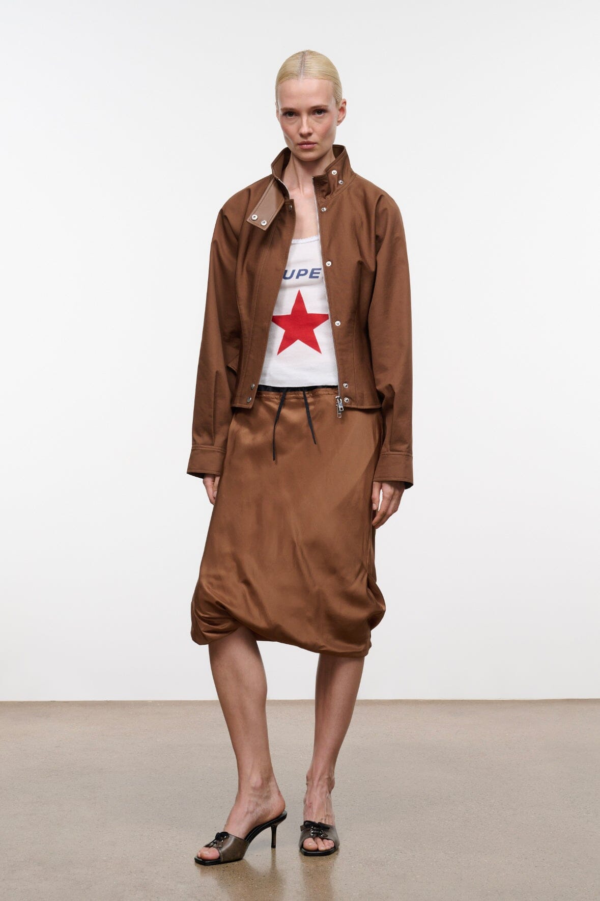 Cigar brown cropped jacket with stand collar, snap buttons, and patch pockets; long skirt visible