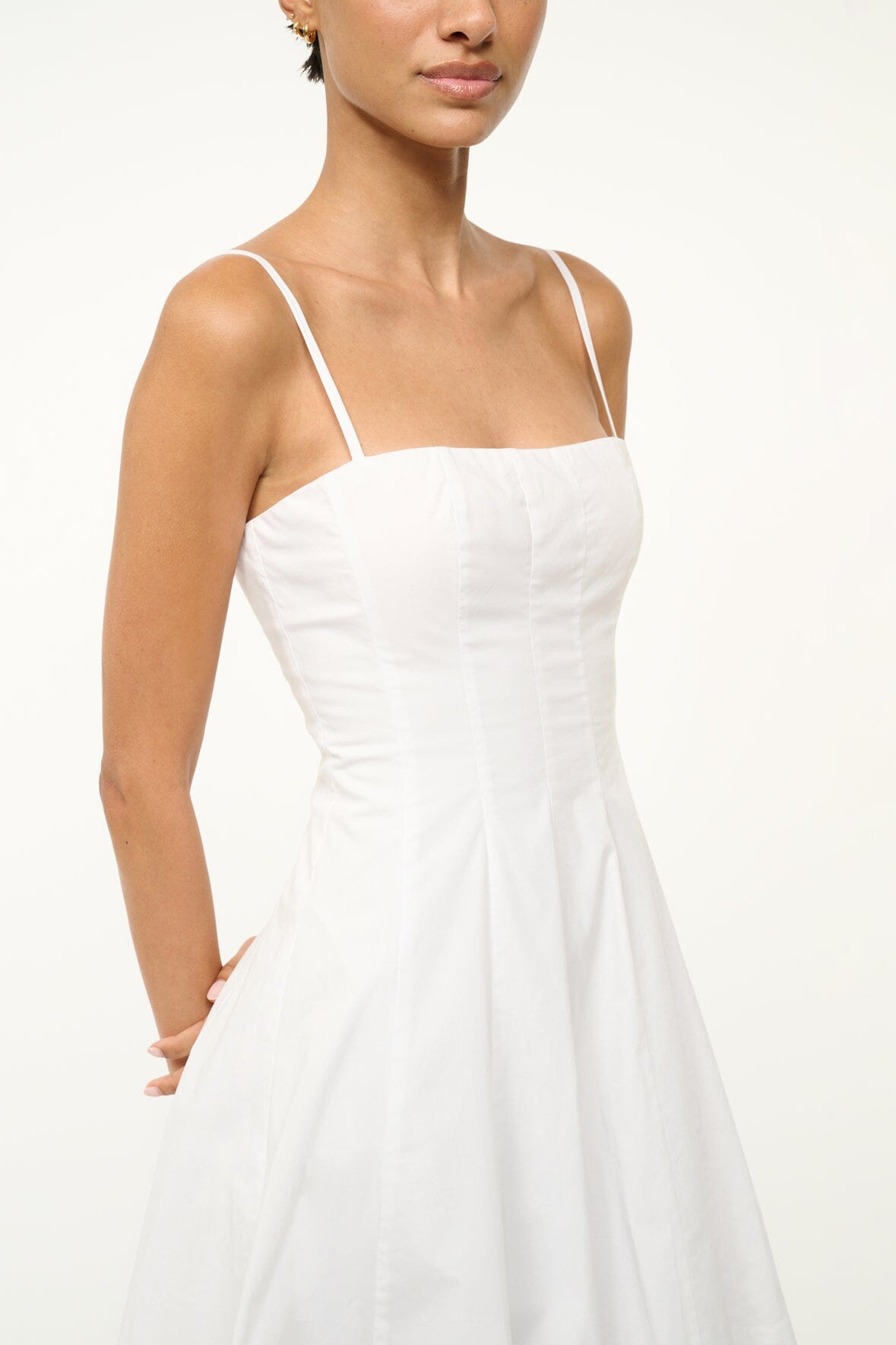 White mini dress bodice close-up with thin straps and flared skirt