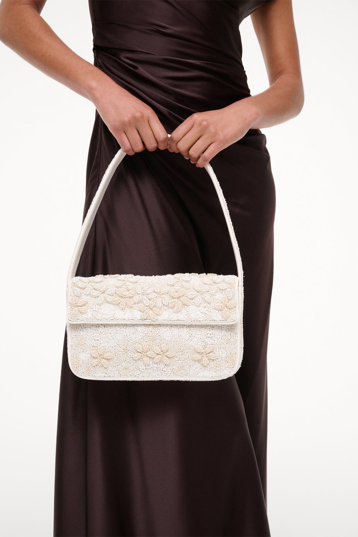 White beaded mini handbag held on shoulder with top handle and front flap.