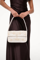 White beaded mini handbag held on shoulder with top handle and front flap.