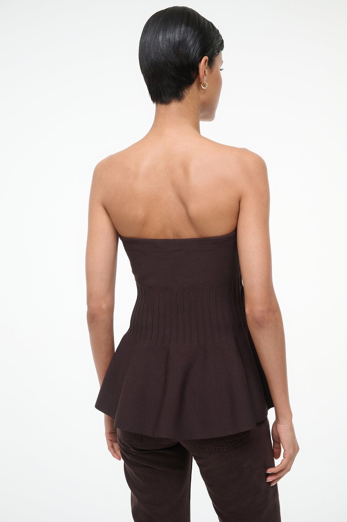 Back view of EVIE strapless peplum top in dark brown with gathered hem