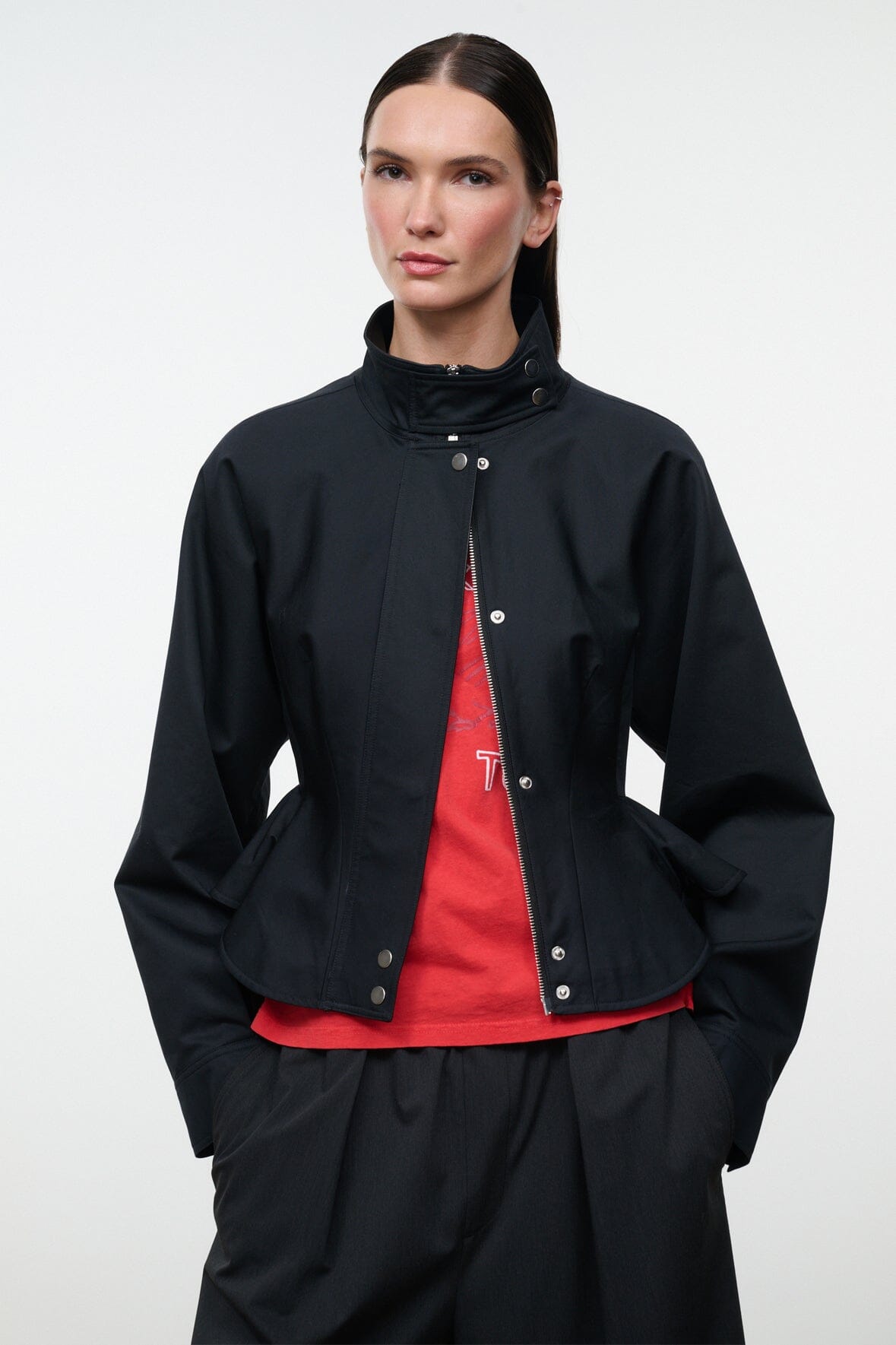 Black snap-front jacket with stand collar, peplum hem, and visible red inner layer