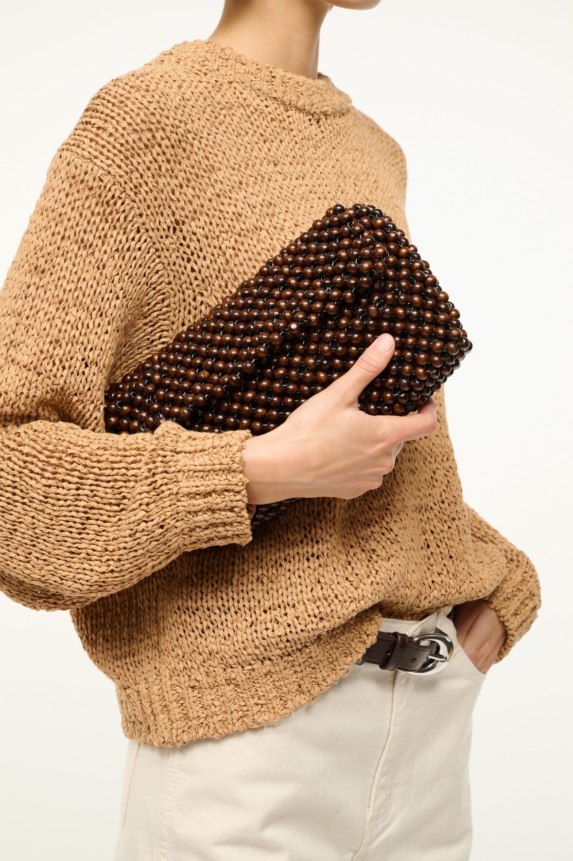 Dark brown beaded shoulder bag with gold-tone chain strap and fabric top, held close-up