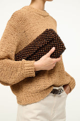 Dark brown beaded shoulder bag with gold-tone chain strap and fabric top, held close-up
