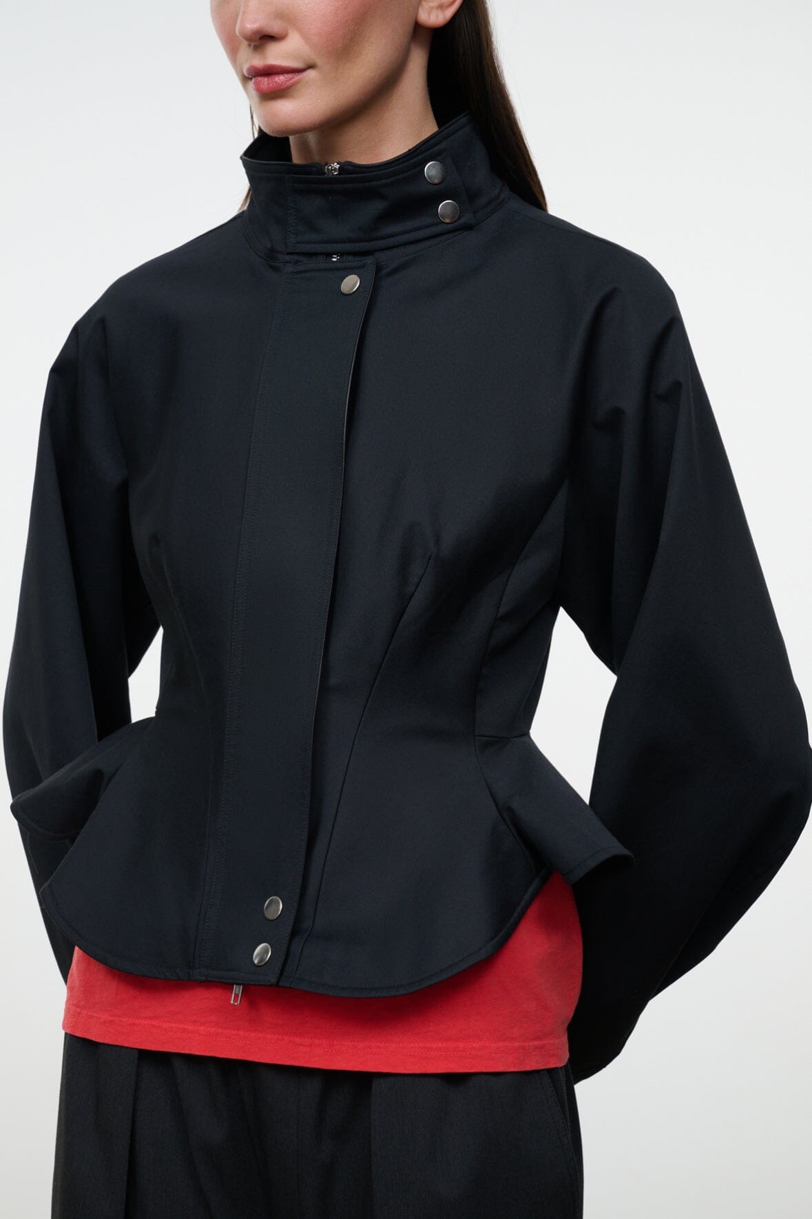 Black jacket with stand collar and snap details, peplum shape over a red top