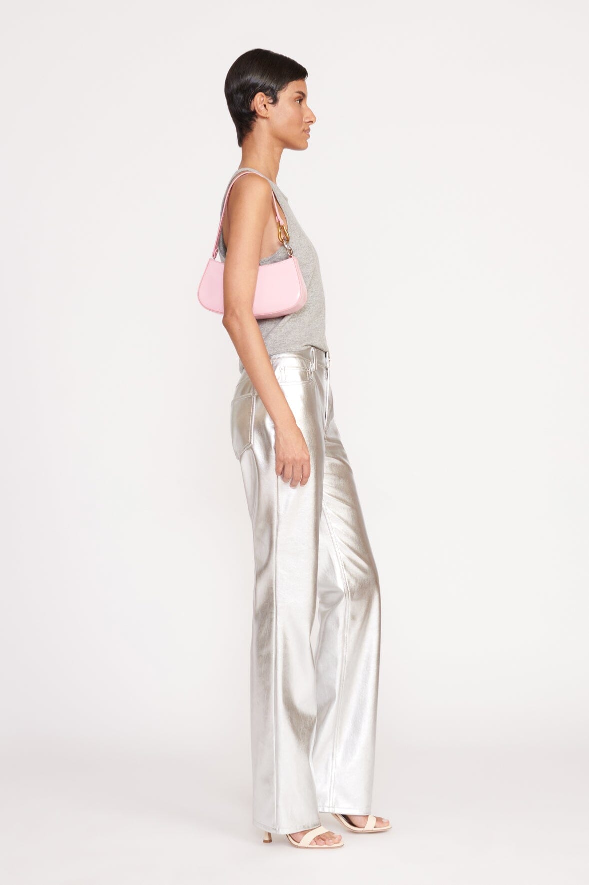 Woman wearing a pink hobo bag with shoulder strap, paired with silver pants