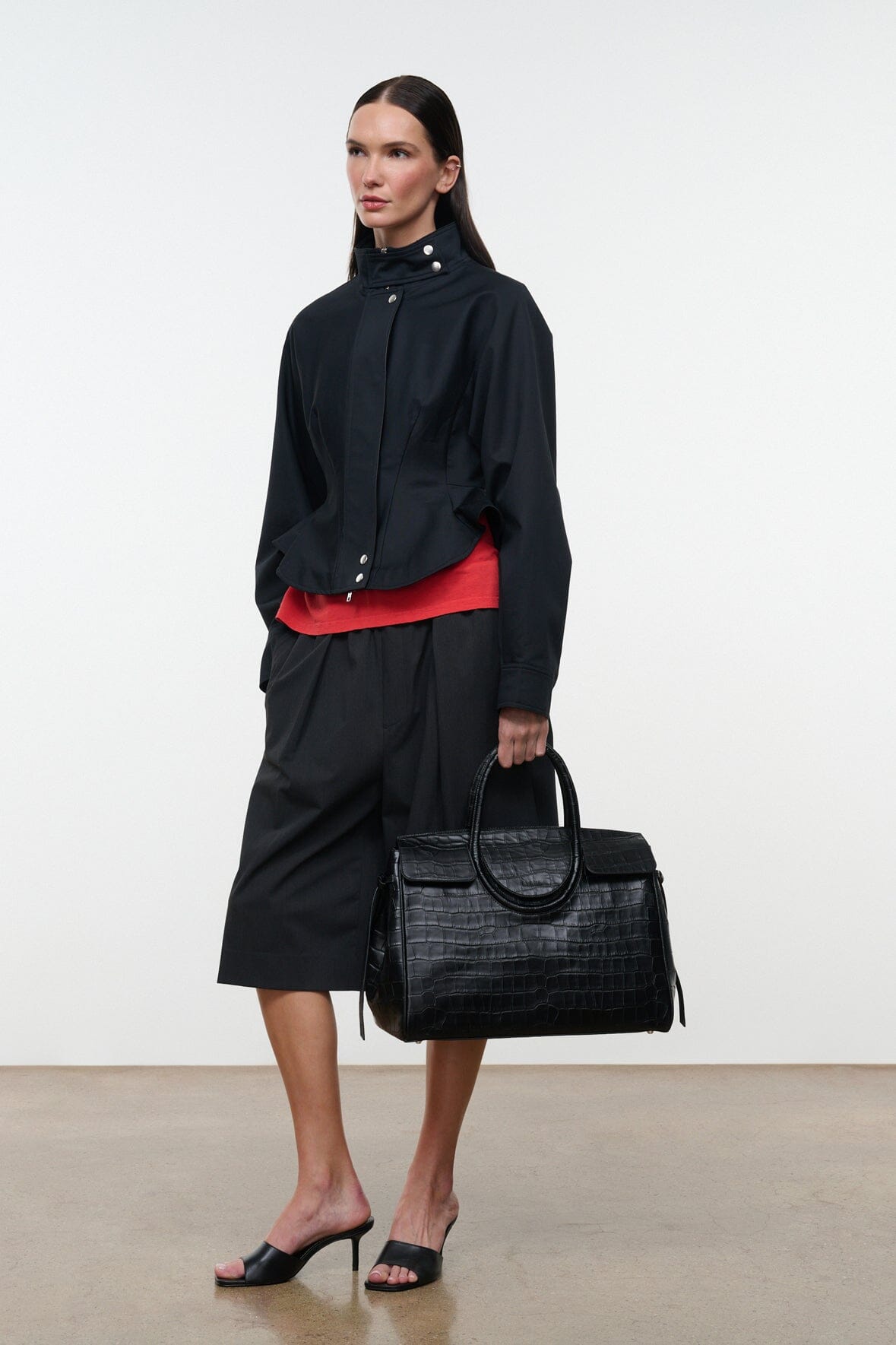 Black jacket with stand collar and snap front, worn with a black tote bag