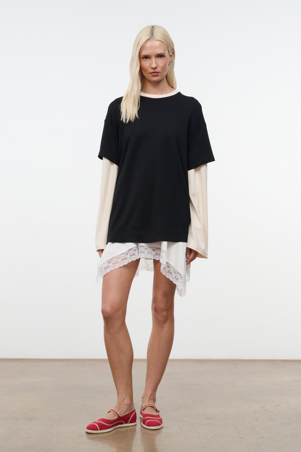 Black oversized tee with short sleeves and ecru underlayer extending past hem