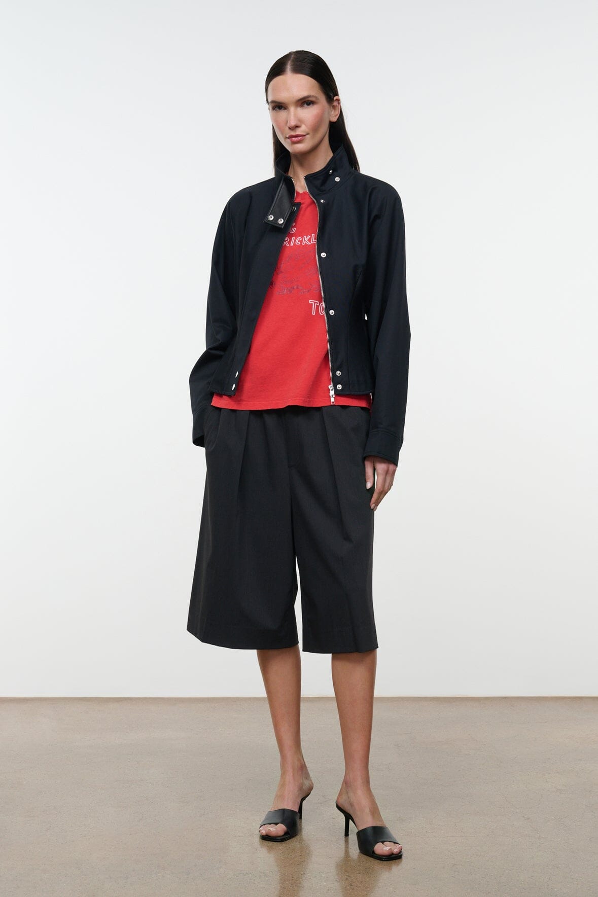 Black stand-collar jacket with snap front, worn open over a red top