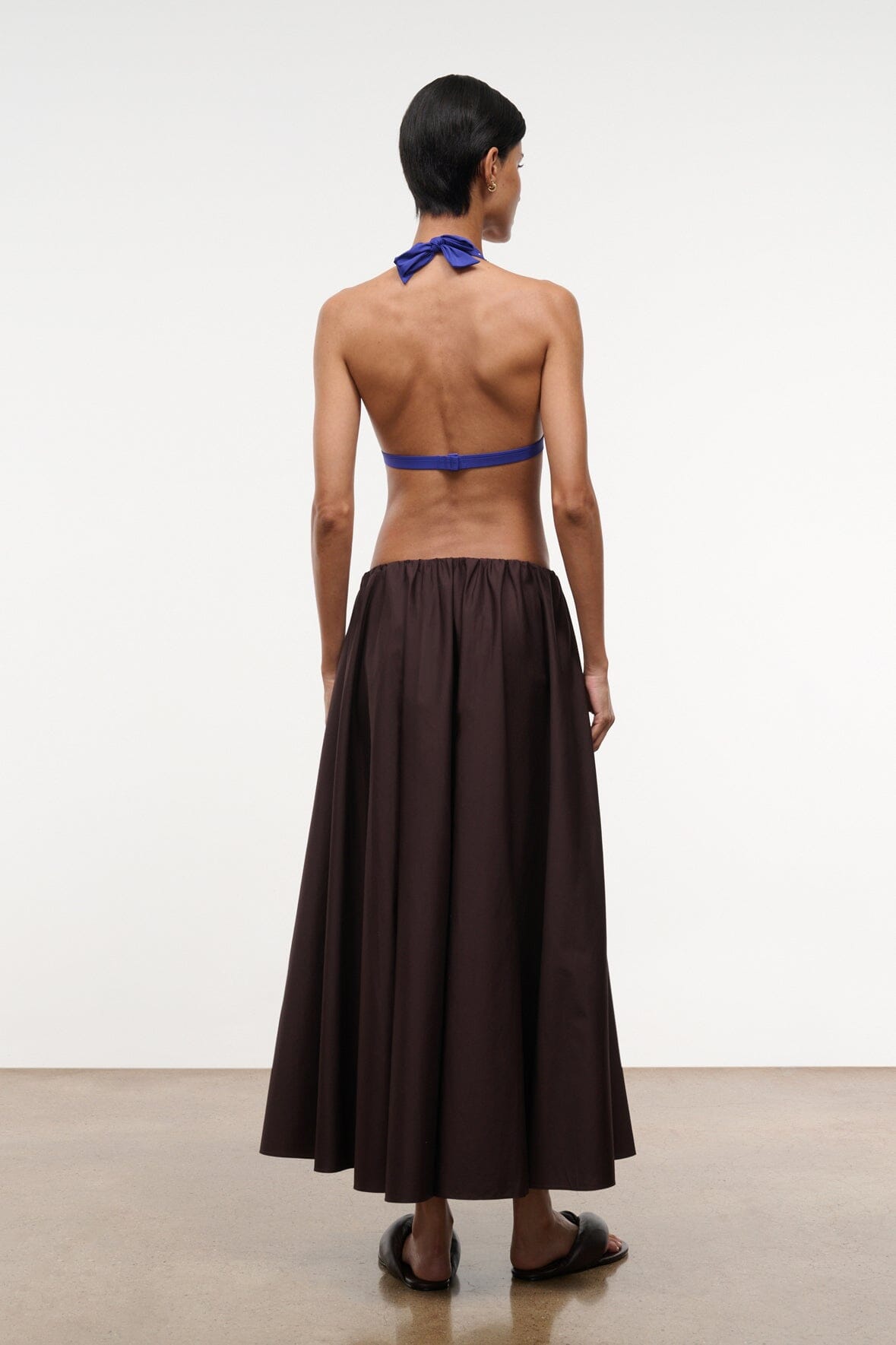 Back view of dark brown midi skirt with gathered waist and flared hem