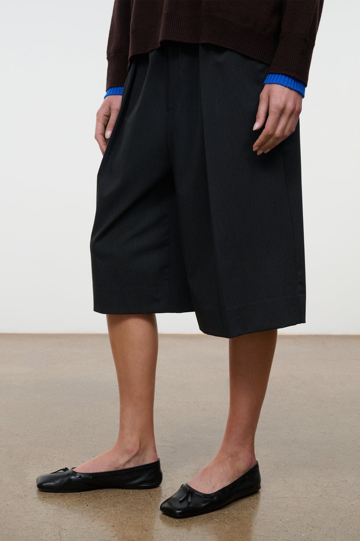 Black flat ballet shoes on model, pointed toe with bow accent