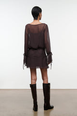Dark brown sheer long-sleeve mini dress with ruched waist and tie-cuff details, back view.