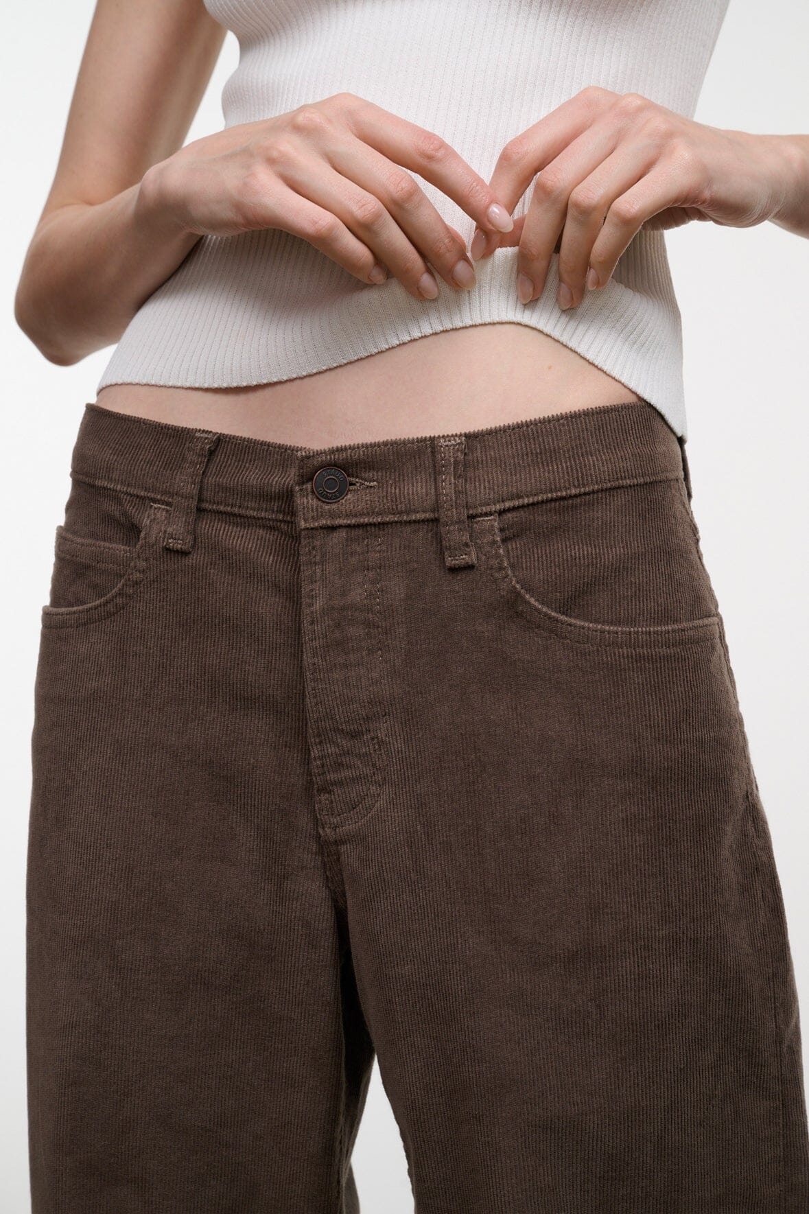 Dark brown corduroy jeans detail: front button and waistband, relaxed wide-leg fit