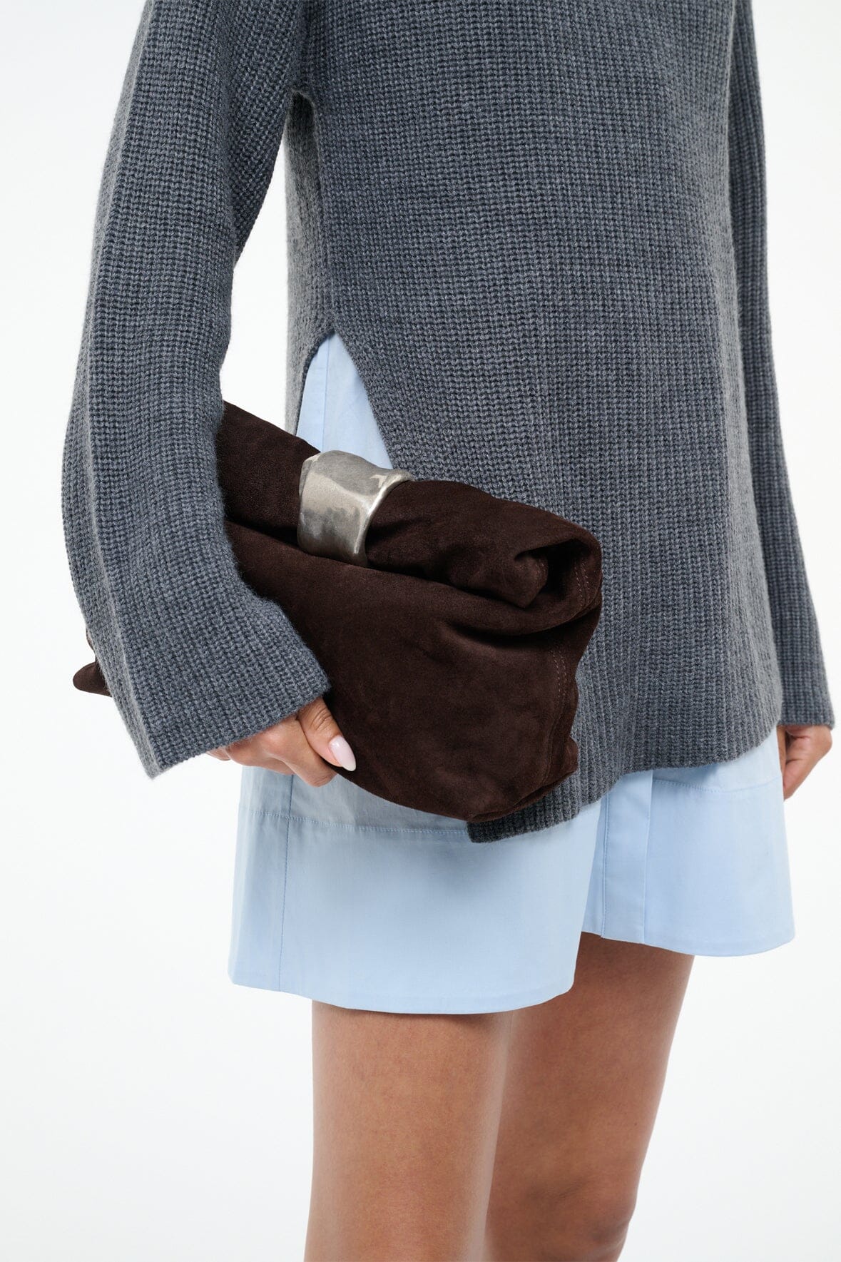 Suede cuff clutch with silver-tone cuff detail, held at side