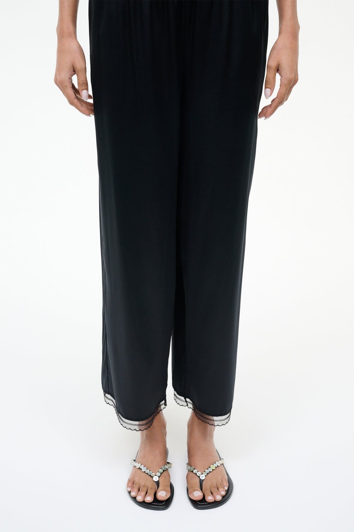 Pearl-beaded black thong sandals worn with cropped dark pants.